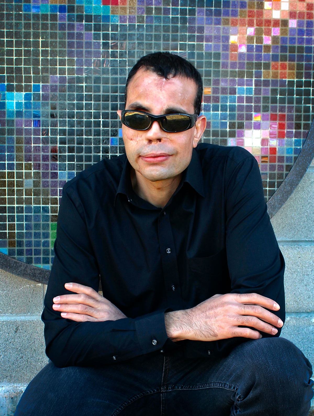 Qusay seated with colored tiles in background